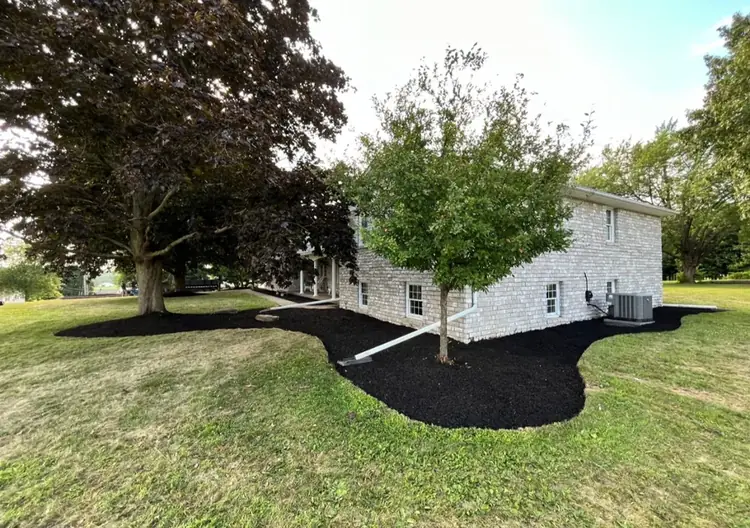Fresh black mulch bed installed around a backyard structure by Going Yard